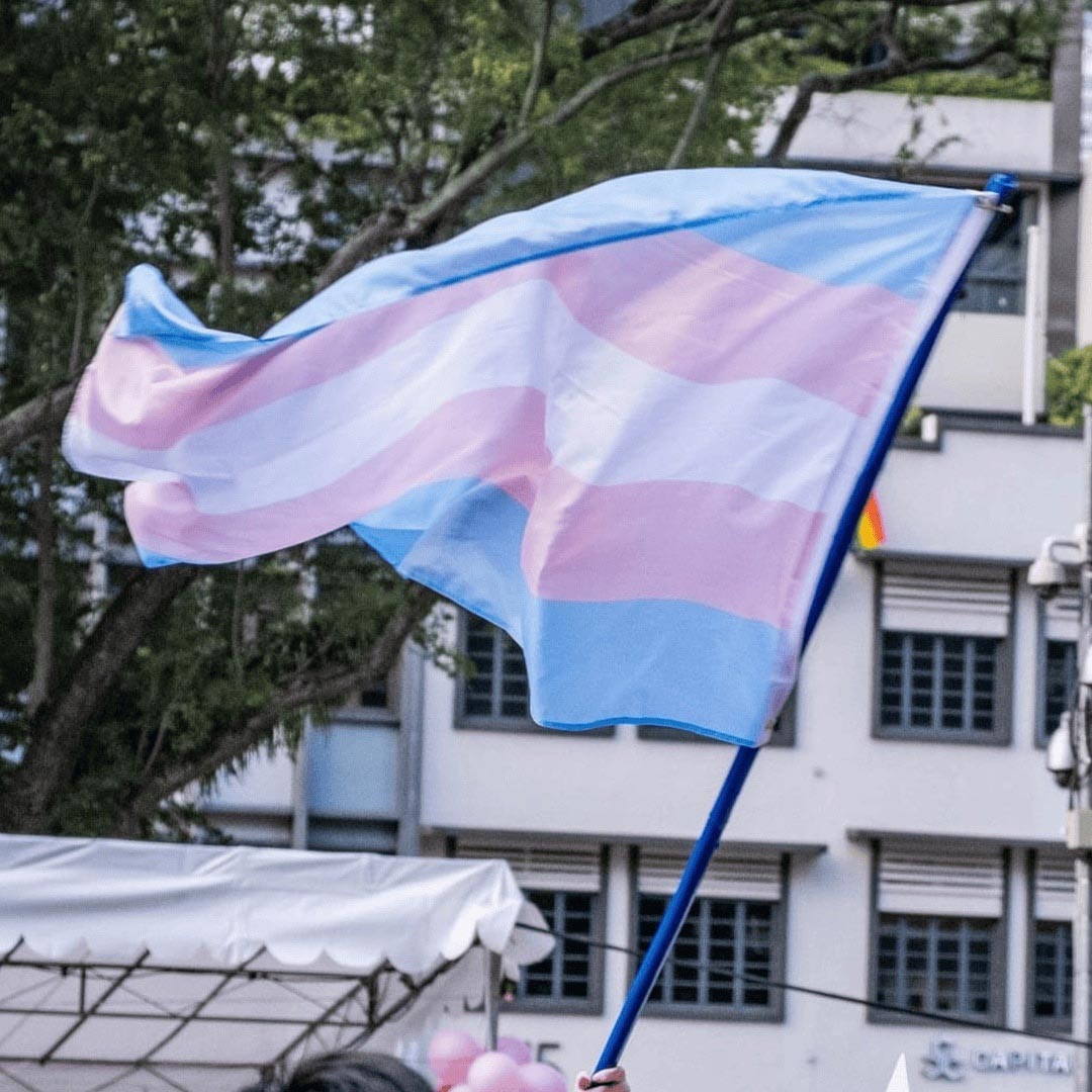 Volunteers smiling and posing behind a TransgenderSG booth at an event